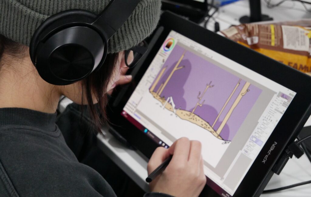Une élève du cursus créatif crée un décors de jeu vidéo sur tablette graphique.